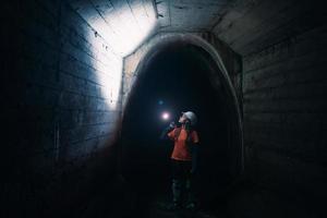 kvinna grävare med ficklampa utforskar de tunnel foto