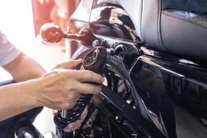 motorcykel mekaniker kolla upp och förändra bak- chock absorberare motorcykel skoter på garage, motorcykel reparera, underhåll och service begrepp foto