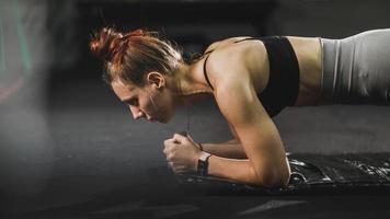 muskulös kvinna håller på med planka övningar under arbetssätt ut på de Gym foto