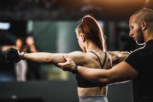 muskulös kvinna håller på med hård Träning med personlig tränare på de Gym foto