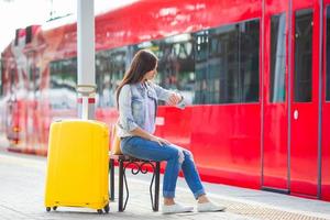 ung vacker flicka med bagage på en järnvägsstation foto