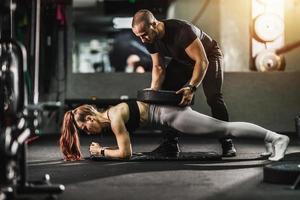 kvinna håller på med hård Träning med tränare på de Gym foto