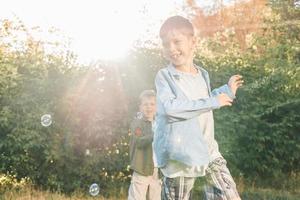 en pojke är spelar med tvål bubblor i en sommar parkera, bland de grönska. foto