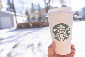 marinette, wi, usa - 14 nov, 2019- koppar av starbucks varm kaffe sätta på vit snö i vinter- trädgård, färsk och varm dryck ta bort concept.starbucks Kafé kaffe affär. foto