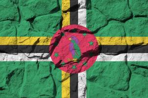 dominica flagga avbildad i måla färger på gammal sten vägg närbild. texturerad baner på sten vägg bakgrund foto