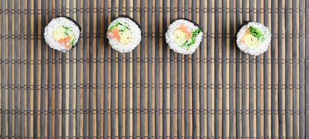 sushi rullar lögner på en bambu sugrör serving matta. traditionell asiatisk mat. topp se. platt lägga minimalism skott med kopia Plats foto