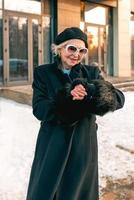 senior eleganta kvinna i basker och elegant svart täcka gående till de företag utnämning. företag, stil, ålder begrepp foto