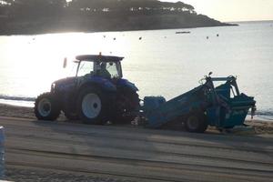 traktor rengöring de vit sand på de strand foto