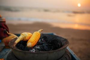 gyllene majs kolvar på de kol i de grill. på de arambol strand på solnedgång. asiatisk, indisk gata mat foto