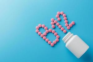 rosa runda vitaminer b12 formad piller på en blå bakgrund spillts från en vit kan foto