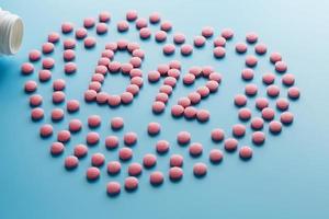 rosa tabletter i de form av b12 i de hjärta på en blå bakgrund, spillts från en vit burk. foto