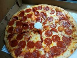 pepperoni pizza med ost och en vit plast Stöd foto