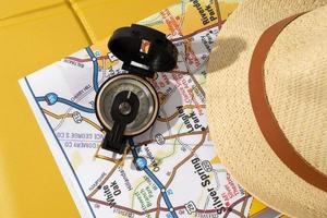 resande Tillbehör på gul väska, karta, hatt, kompass foto