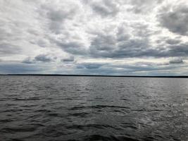 landskap av de natur av de horisont linje med en se av de Strand, vatten med vågor från de mitten av de sjö i de kall molnig väder foto