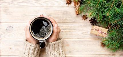 kvinna händer innehav kaffe cupon trä- tabell med jul dekoration. topp se baner med kopia Plats foto