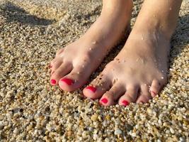 kvinna ben, fötter med en skön röd pedikyr mot de bakgrund av smulig gul gyllene sand på semester på de strand i en värma tropisk östra paradis Land sydlig tillflykt foto