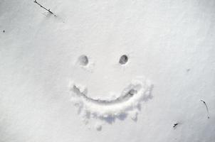 söt smiley ansikte dragen på snö i vinter- dag. foto