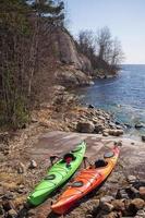 två kajaker är parkerad på de klippig Strand av de sjö på en solig vår dag. säsong öppning. aktiva resten. foto