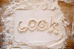 de handskriven ord laga mat är skriven på mjöl stänkte på en trä- tabell och en rektangulär skriva ut. foto