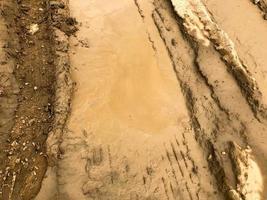 textur av en smutsig dålig smuts väg smuts väg med vattenpölar och lera torkning lera med sprickor och hjulspår. av vägen. de bakgrund foto