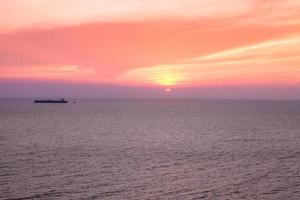 skön solnedgång över hav strand, med moln på skymning himmel skön färger bakgrund. foto