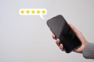 kvinna hand använder sig av en smartphone med en femstjärnigt dyka upp ikon för respons, recension, tillfredsställelse service. foto