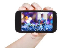 hand innehar smartphone med xmas fortfarande liv foto