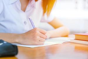 universitet flicka hand skrivande. tonåring håller på med läxa examen skola begrepp. foto