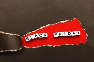 ringla av trasig svart papper på röd bakgrund. reklam och svart fredag försäljning begrepp. foto