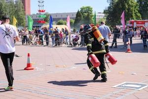 en brandman i en eldfast kostym och en hjälm löpning med röd brand släckare till släcka en brand på en brand sport konkurrens, belarus, minsk, 08.08.2018 foto