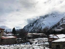 små sten hus, byggnader i de by på en skön berg kall vinter- tillflykt med hög berg toppar dimma och snö täckt stenar för åka snowboard och skidåkning mot en blå himmel foto