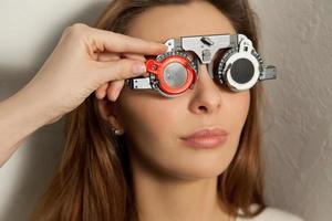 Söt kvinna checkar syn i ett ögonläkare med korrigerande linser foto