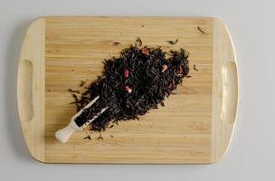en blandning av torr svart te och bitar av torkades jordgubbar som en bakgrund. isolerat på en trä- yta. foto