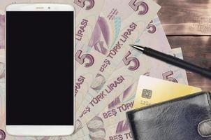 5 turkiska lire räkningar och smartphone med handväska och kreditera kort. e-betalningar eller e-handel begrepp. uppkopplad handla och företag med bärbar enheter foto