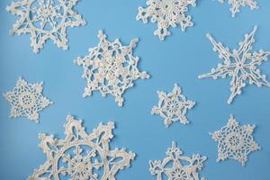 topp se av handgjort vit virka snöflingor på blå bakgrund. glad jul och Lycklig ny år begrepp. foto