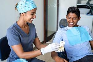 ung tandläkare förklara till en patient i de dental studio. foto