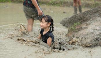 liten flickor ha roligt spelar i de lera i de gemenskap fält foto