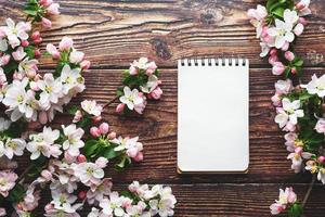 sakura blommar på en mörk rustik trä- bakgrund med en anteckningsbok. vår bakgrund med blomstrande aprikos grenar och körsbär grenar foto