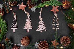 jul eller ny år mörk bakgrund med gran grenar och hantverk gåva trä- jul träd hängen, xmas svart styrelse inramade med säsong dekorationer, foto