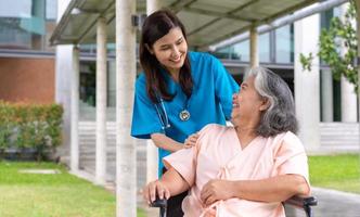 asiatisk omsorgsfull vårdgivare eller sjuksköterska som tar hand om patienten i rullstol. begreppet lycklig pensionering med omsorg från en vårdgivare och besparingar och senior sjukförsäkring, en lycklig familj foto