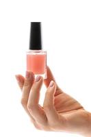 kvinna hand med skön franska manikyr innehav flaska av rosa nagel putsa mot vit bakgrund foto