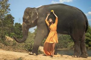 kvinna i skön orange klänning och mäktig elefant foto