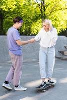 sorglös tonåring par i en skate-park. kille ger en lektion av skateboard för hans flickvän. foto