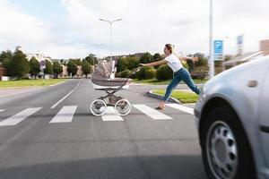 hänsynslöst mor påfrestande till fånga henne bebis pråm rullad ut på de väg foto