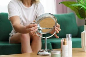 kvinna med en runda spegel och rör av kosmetika på de tabell foto