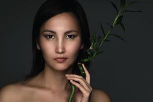 skön asiatisk kvinna med en bambu växt i henne händer foto