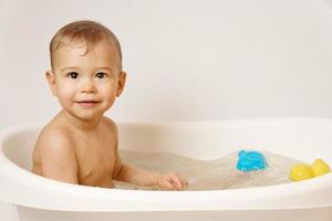 förtjusande liten pojke är tar en bad i värma vatten. foto