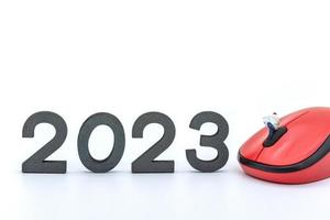 2023 företag ny år begrepp. närbild av affärsman miniatyr- siffror Sammanträde och läsning en tidning på dator mus med siffra på vit bakgrund. foto
