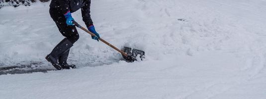 ung man skotta snö från de gående väg i vinter. foto