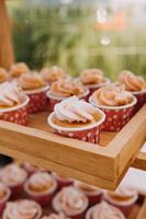 gourmet muffins med vit smörkräm glasyr och strössel på trä- bakgrund foto